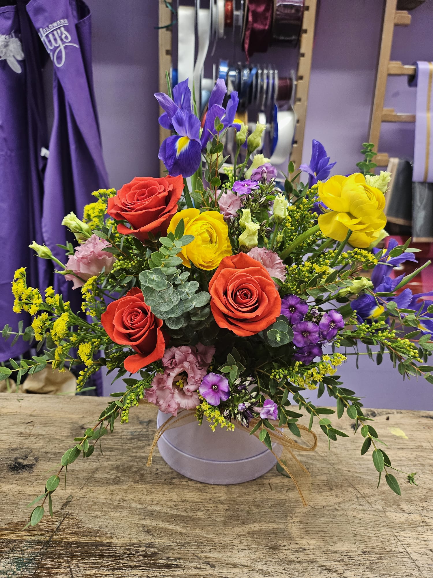Lotty's Signature Hatbox with red roses, yellow ranunculus, purple iris and pink lisianthus