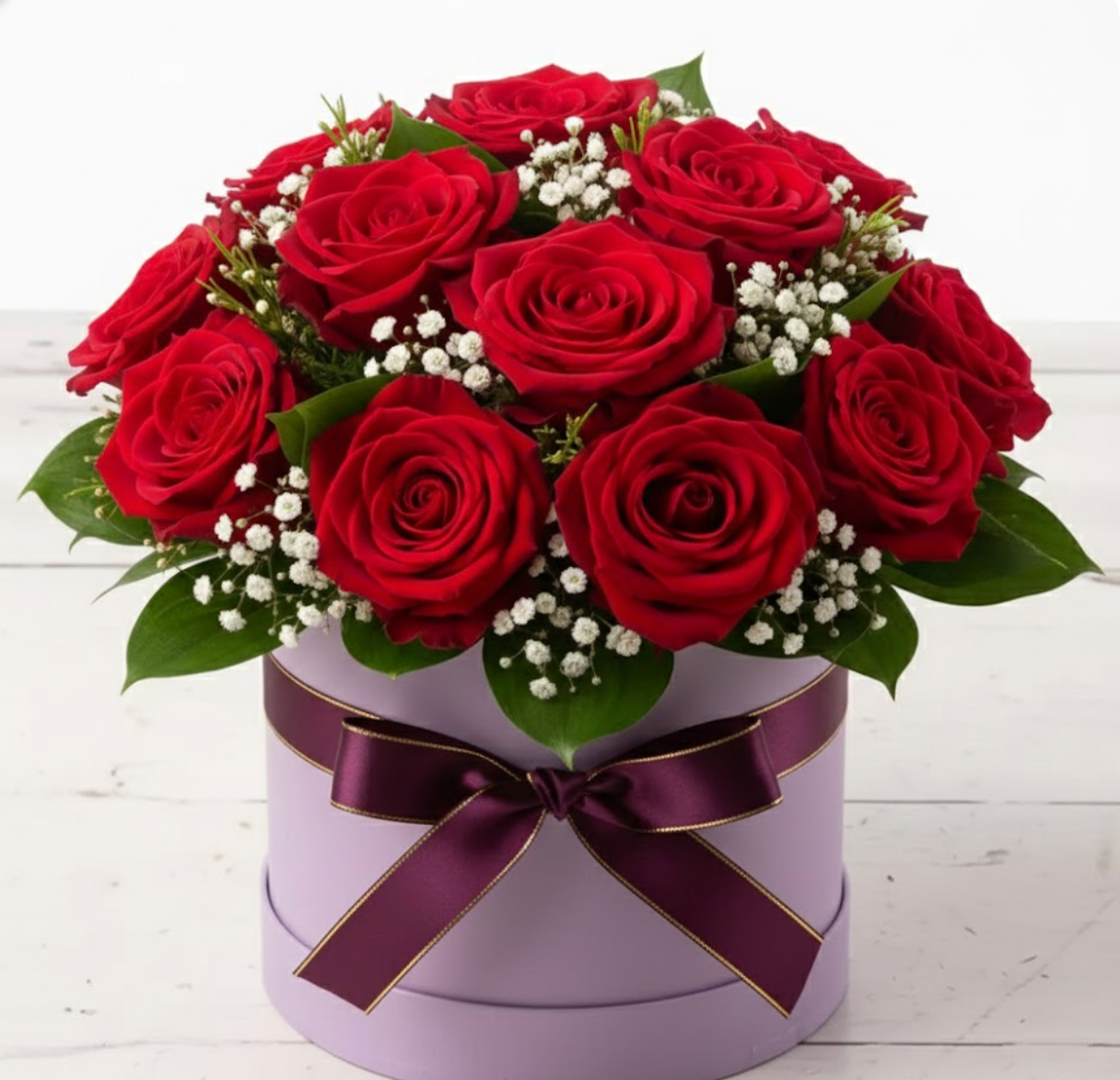Bouquet of red roses in a purple box with a purple ribbon on a white wooden surface