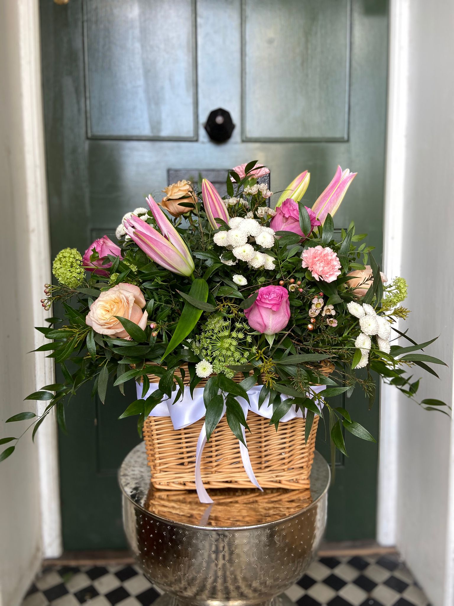 Wicker basket arrangement with pink lilies, roses and white flowers