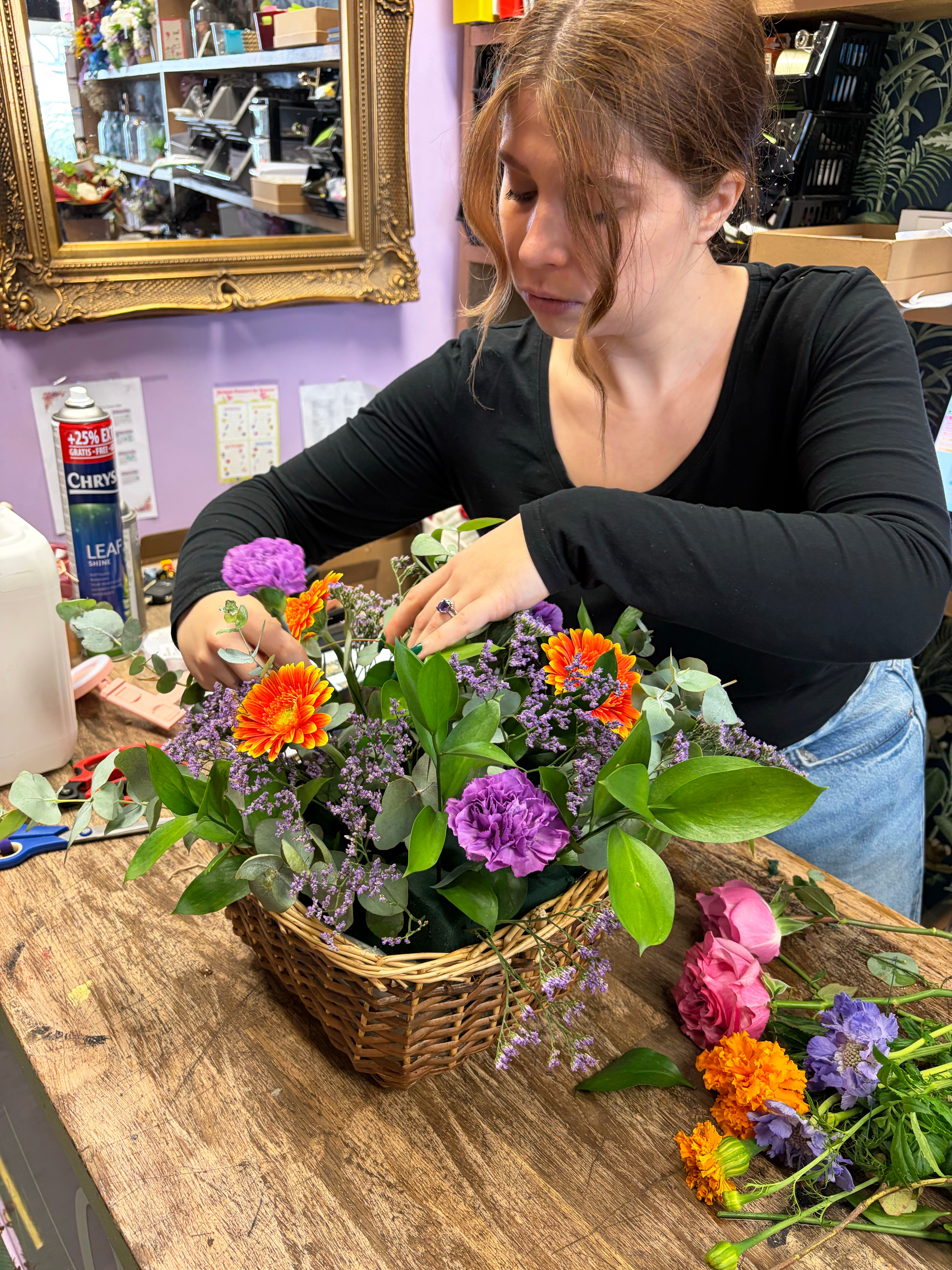 Florist holding a colourful basket arrangement of mixed flowers