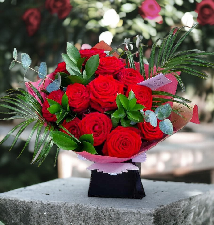 Luxury red rose bouquet with palm leaves, eucalyptus and red wrapping