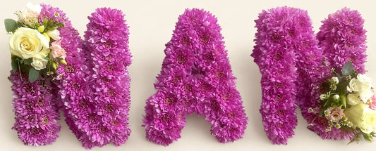 Purple chrysanthemum funeral letters spelling NAN with cream rose corsages