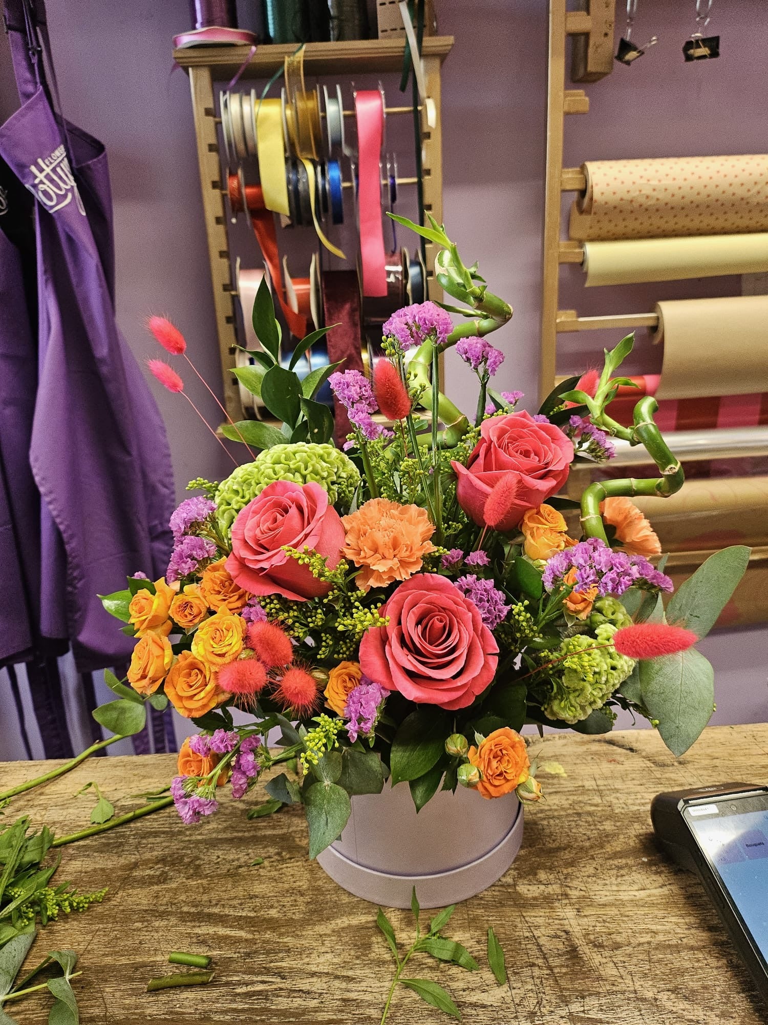 Colourful Lotty's Signature Hatbox with coral roses, orange spray roses, green celosia and purple statice