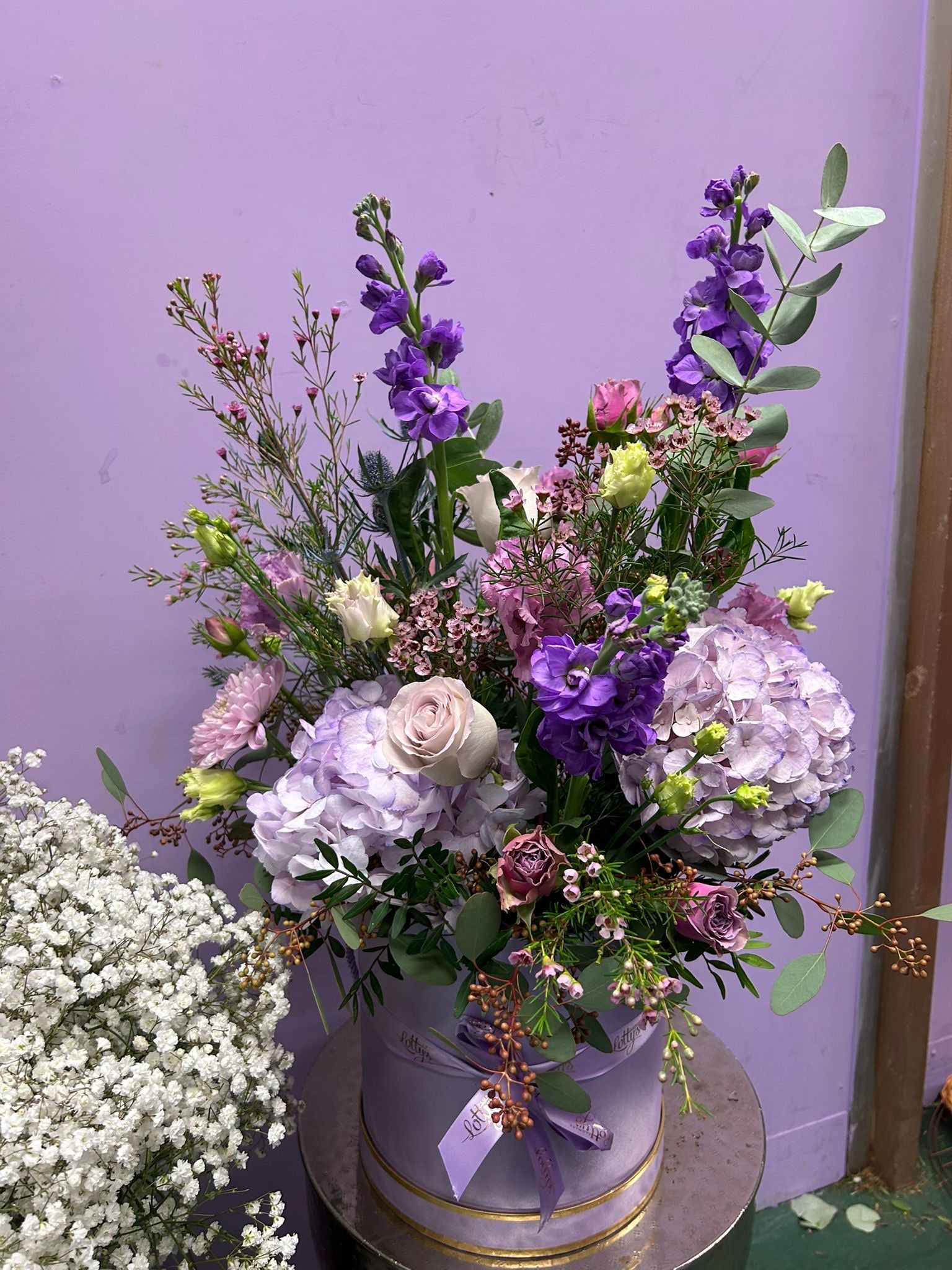 Pink hatbox with hot pink gerberas, pink roses and peonies with greenery and a lilac ribbon