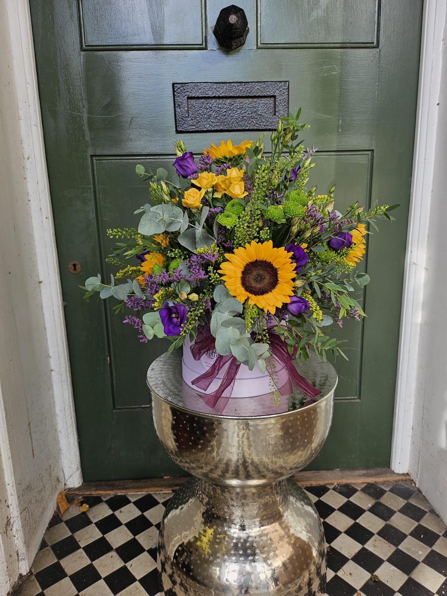 Bright hatbox with yellow roses, orange germini, purple iris and hypericum berries in a green box