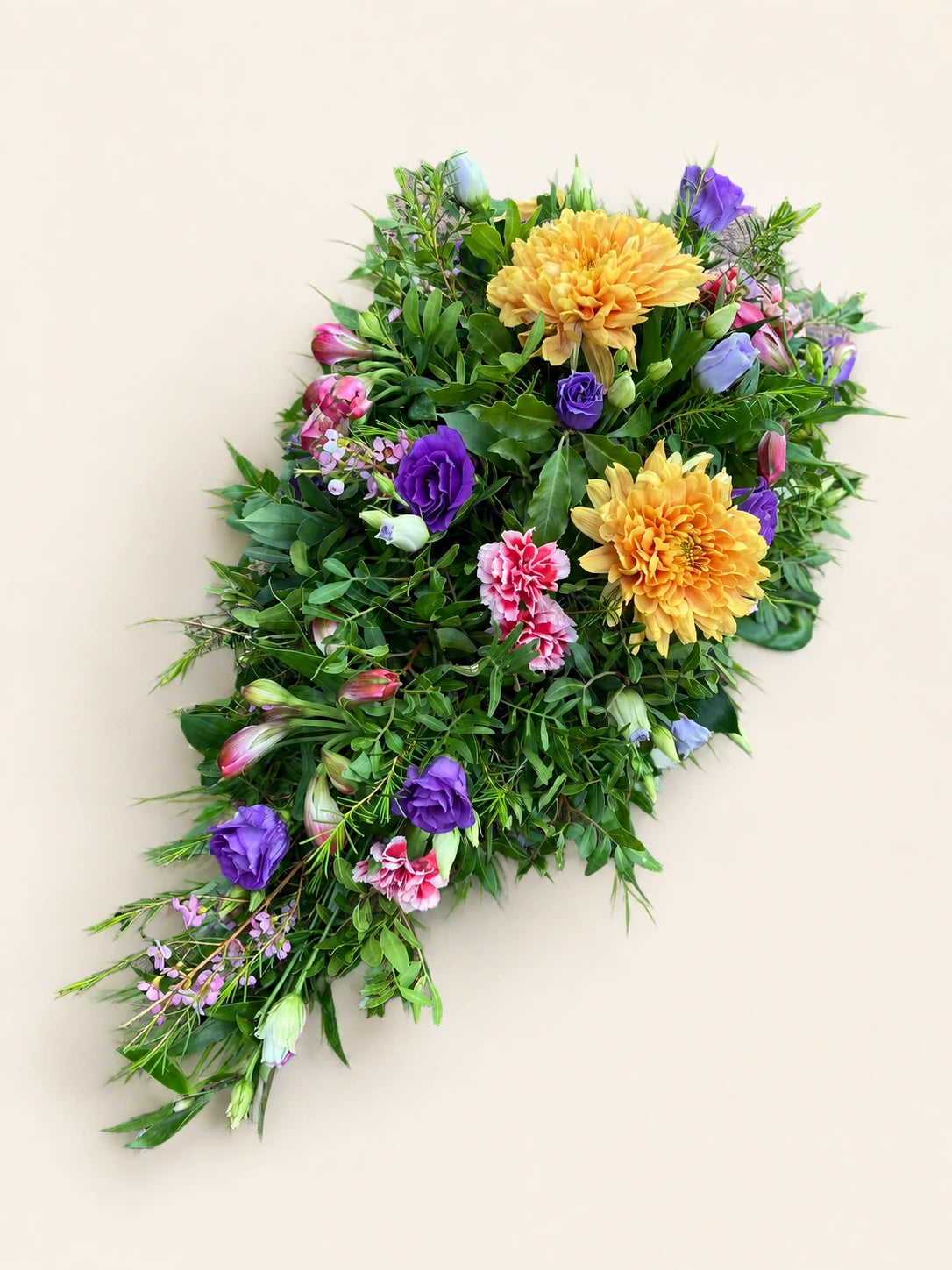 Single-ended funeral spray with orange chrysanthemums, purple and pink flowers and green foliage