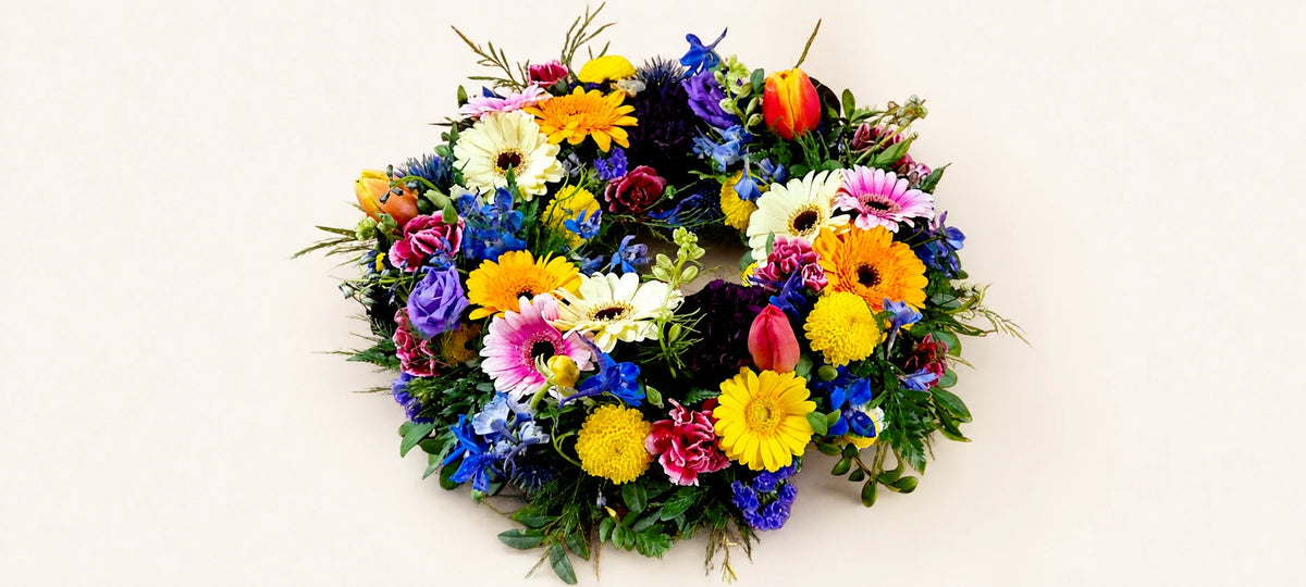 Multicoloured funeral wreath with yellow and white daisies, pink gerberas and purple flowers