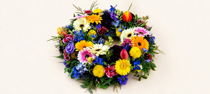 Multicoloured funeral wreath with yellow and white daisies, pink gerberas and purple flowers