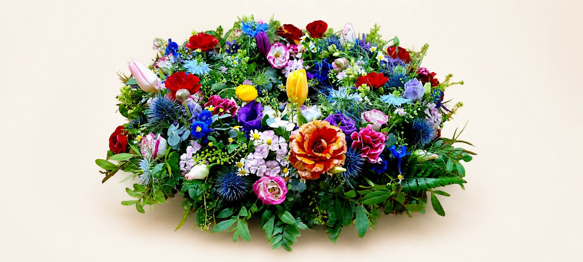 Side view of a colourful funeral wreath with orange roses, red flowers and blue hydrangeas