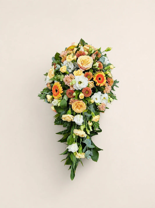 Single-ended funeral spray with peach roses, orange gerberas, cream flowers and green foliage