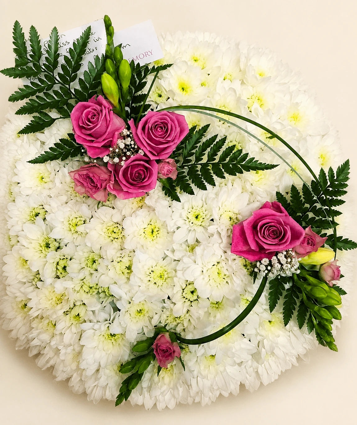 Close view of a white chrysanthemum posy with pink rose clusters, fern leaves and curved grasses