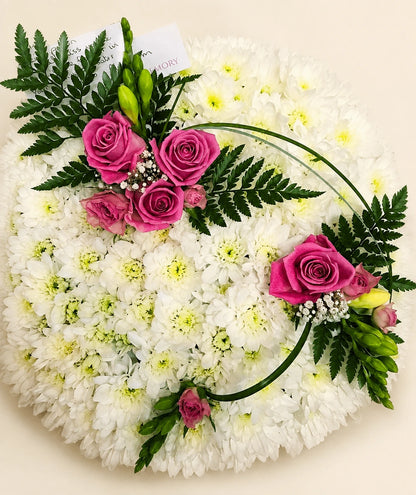 Close view of a white chrysanthemum posy with pink rose clusters, fern leaves and curved grasses