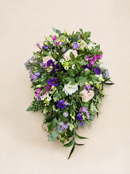 Single-ended funeral spray with pale pink roses, purple and white flowers and green foliage