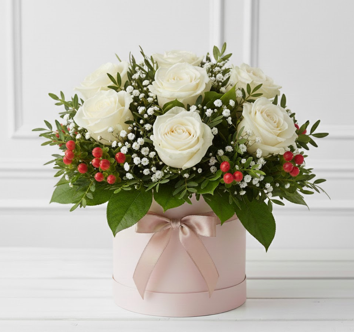 Bouquet of white roses with greenery and red berries in a pink box on a white background