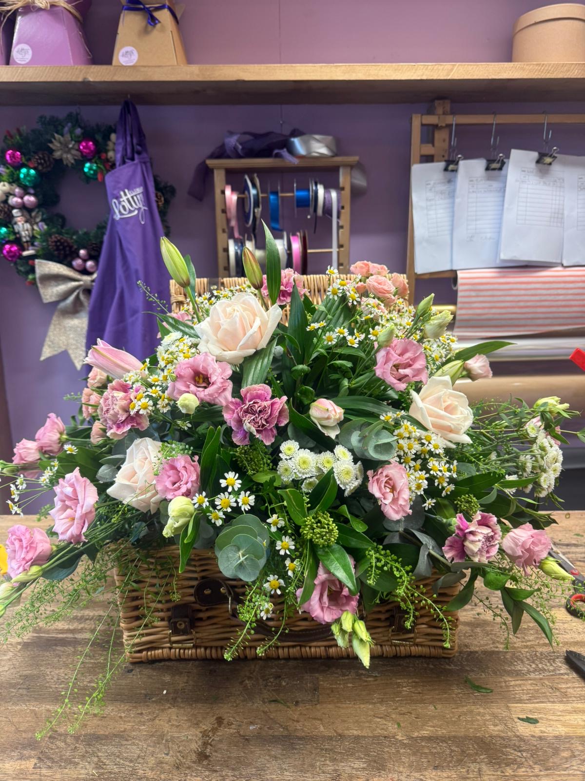 Colourful basket arrangement of pink, purple and white flowers in Lotty's Flowers shop