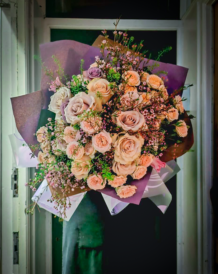 The Veronica bouquet with light purple and peach roses, baby's breath and green foliage