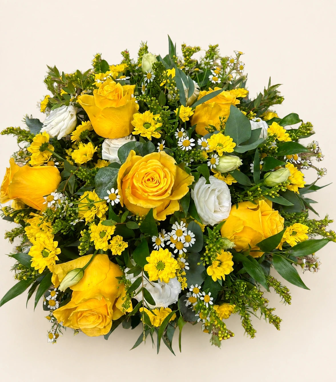 Overhead view of a yellow rose funeral posy with white daisies, yellow flowers and greenery