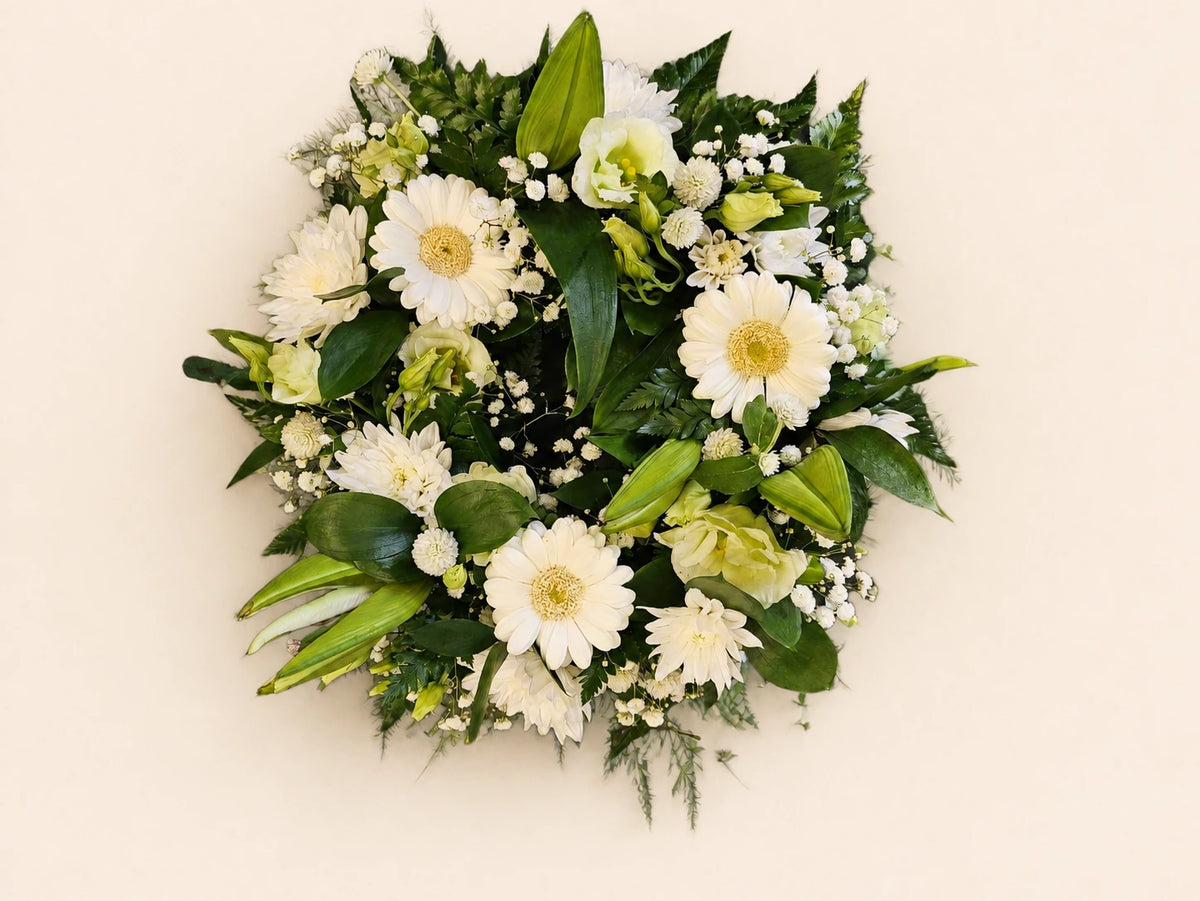 Round white funeral posy with gerberas, roses, lily buds, small white flowers and green foliage