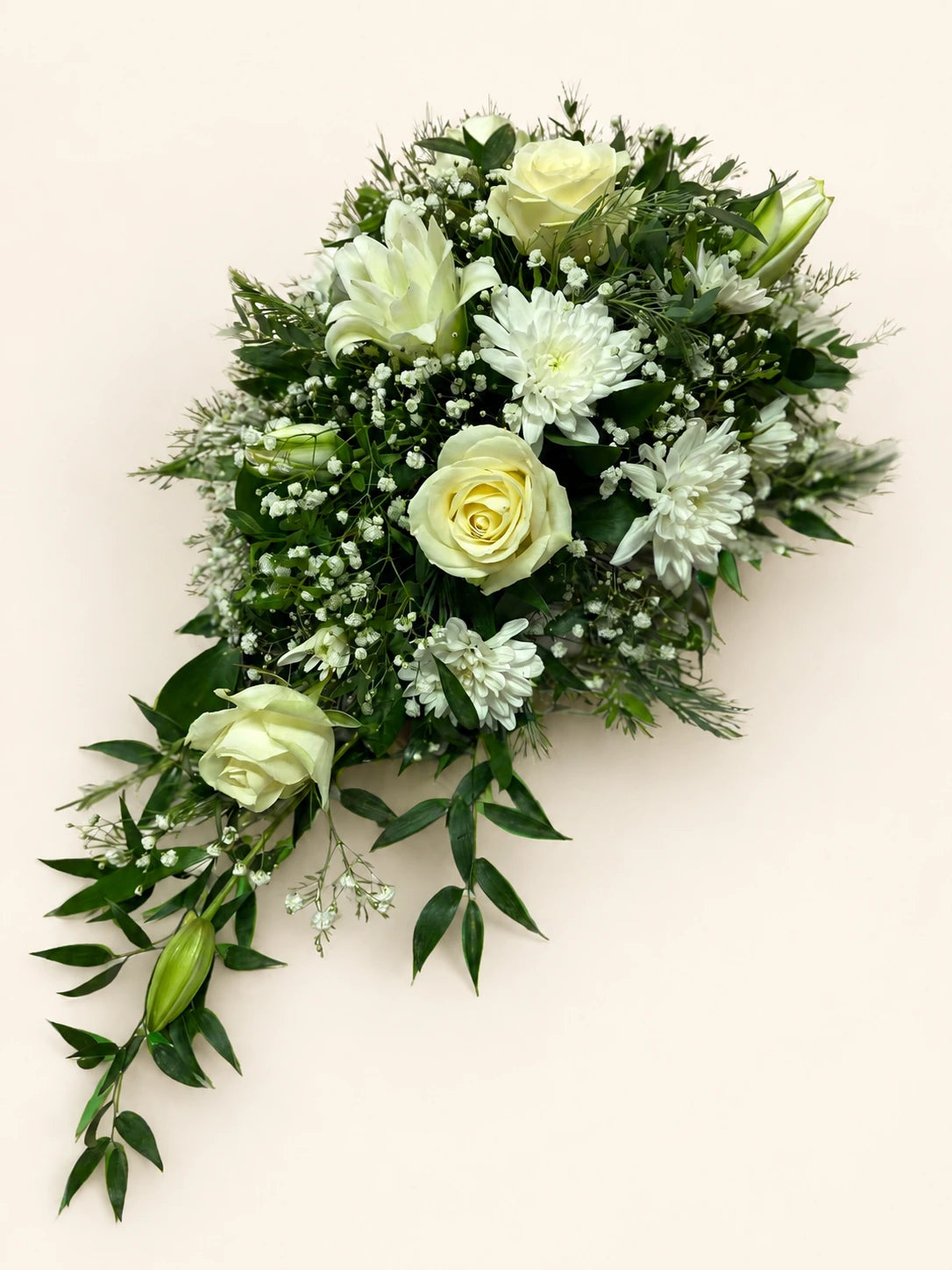 White single-ended funeral spray with cream roses, white flowers and trailing green foliage