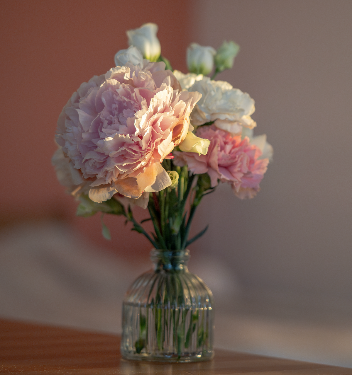 Pink carnations arranged in a vase as a wedding table flower detail.