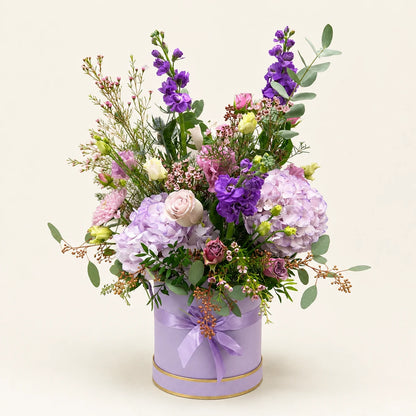 Lilac hydrangeas, purple stock and pale roses with eucalyptus in a tall lilac Signature Hatbox with a ribbon bow