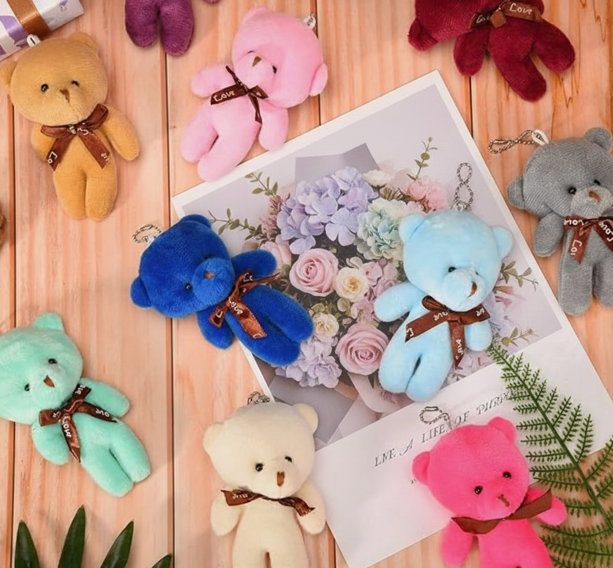 Mini plush teddy bear keyrings in assorted bright and pastel colours, each with a brown ribbon bow