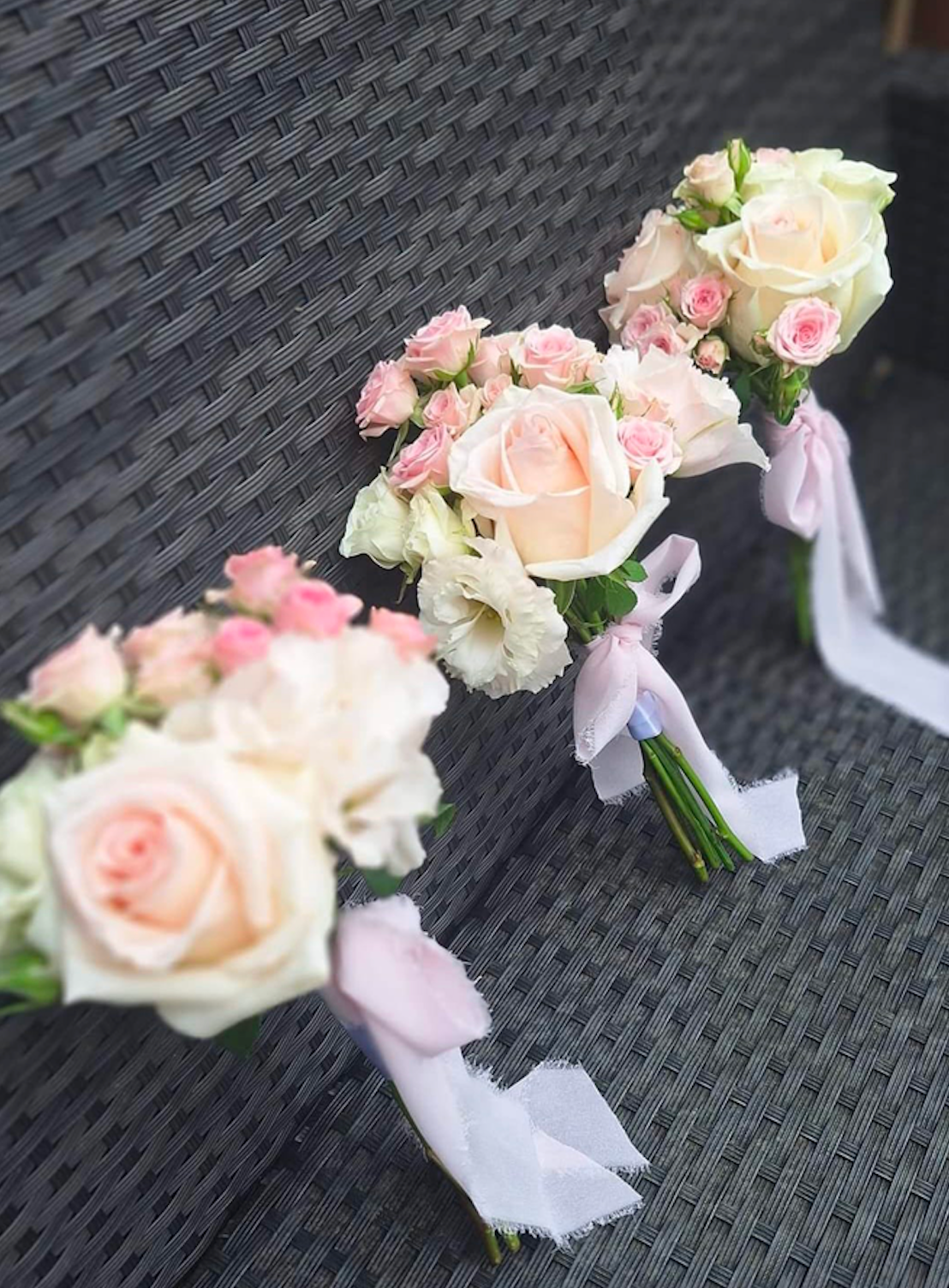 Three small pink rose posies with ribbon-wrapped stems for a wedding party.