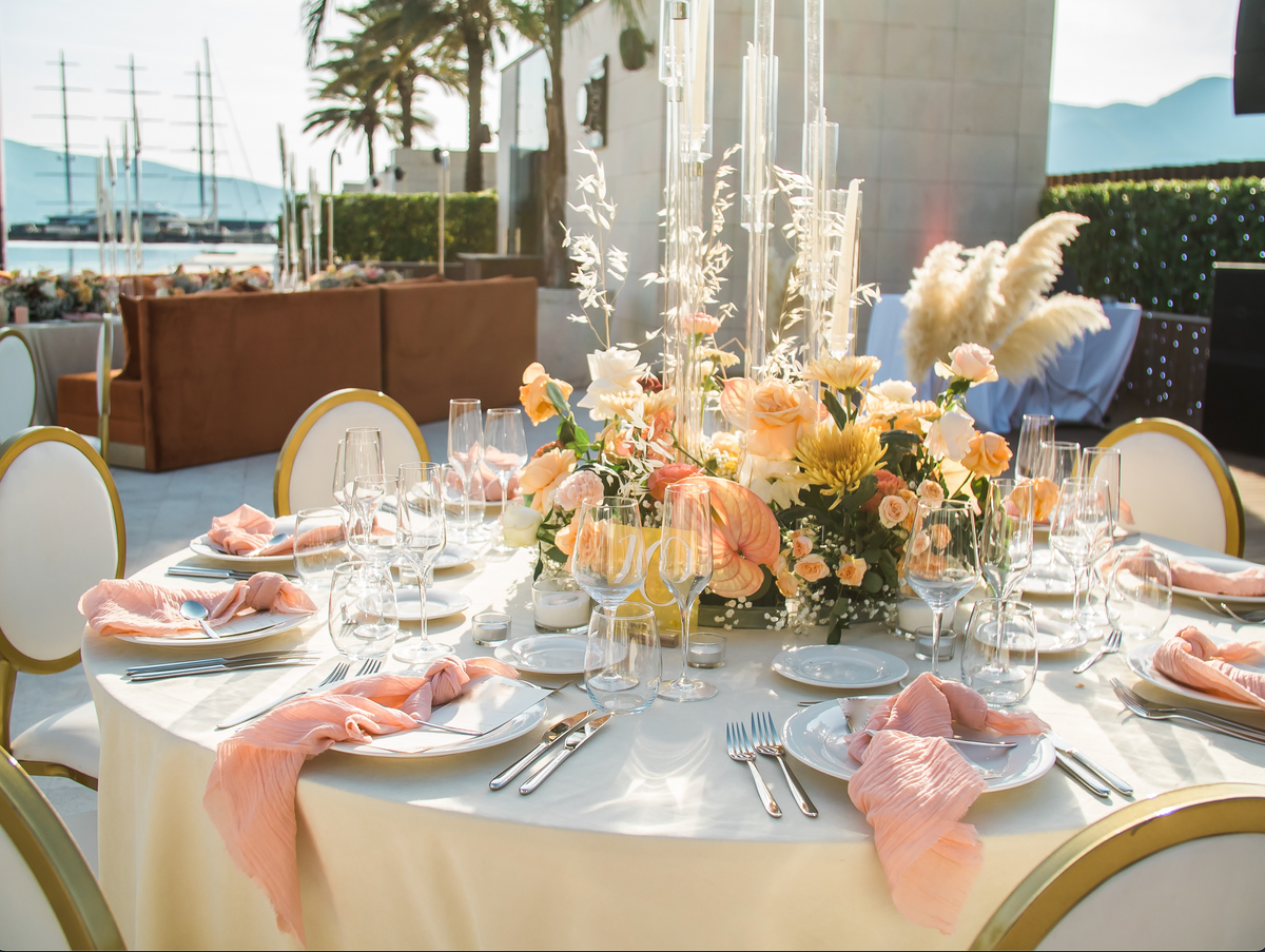 Wedding reception table set with floral decorations, glassware and place settings.