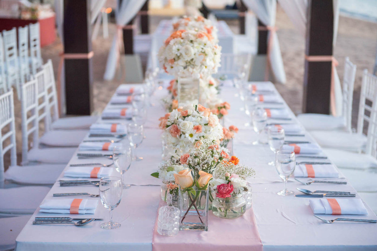 Wedding reception table decorated with flowers, candles and place settings.